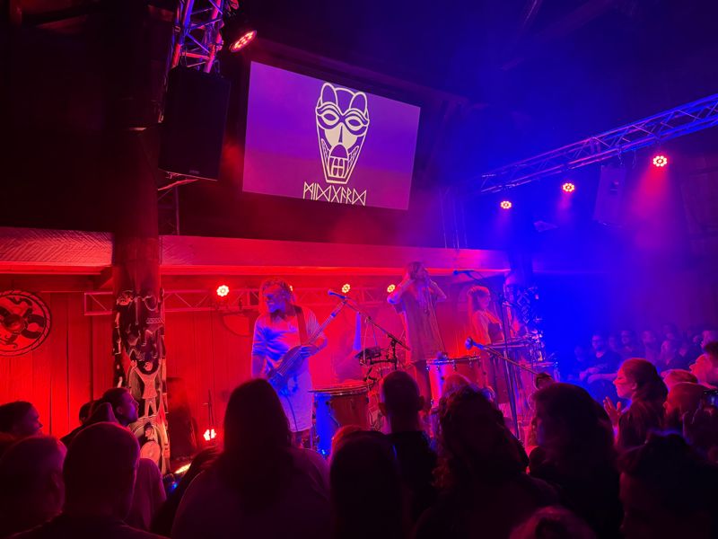 Konsert i Gildehallen i rødt og blått lys med Midgardsblot-logoen på skjermen