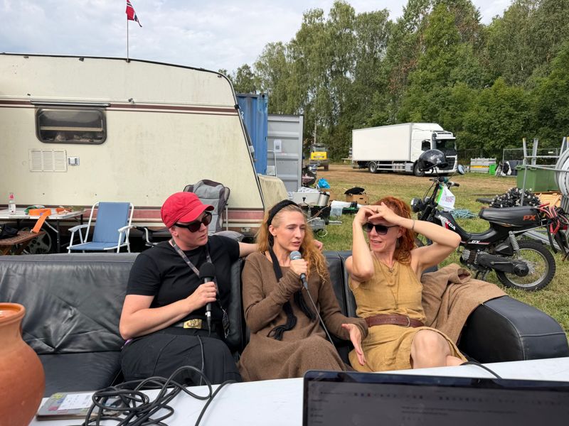 Tre medlemmer av Songleikr i intervju i en skinnsofa